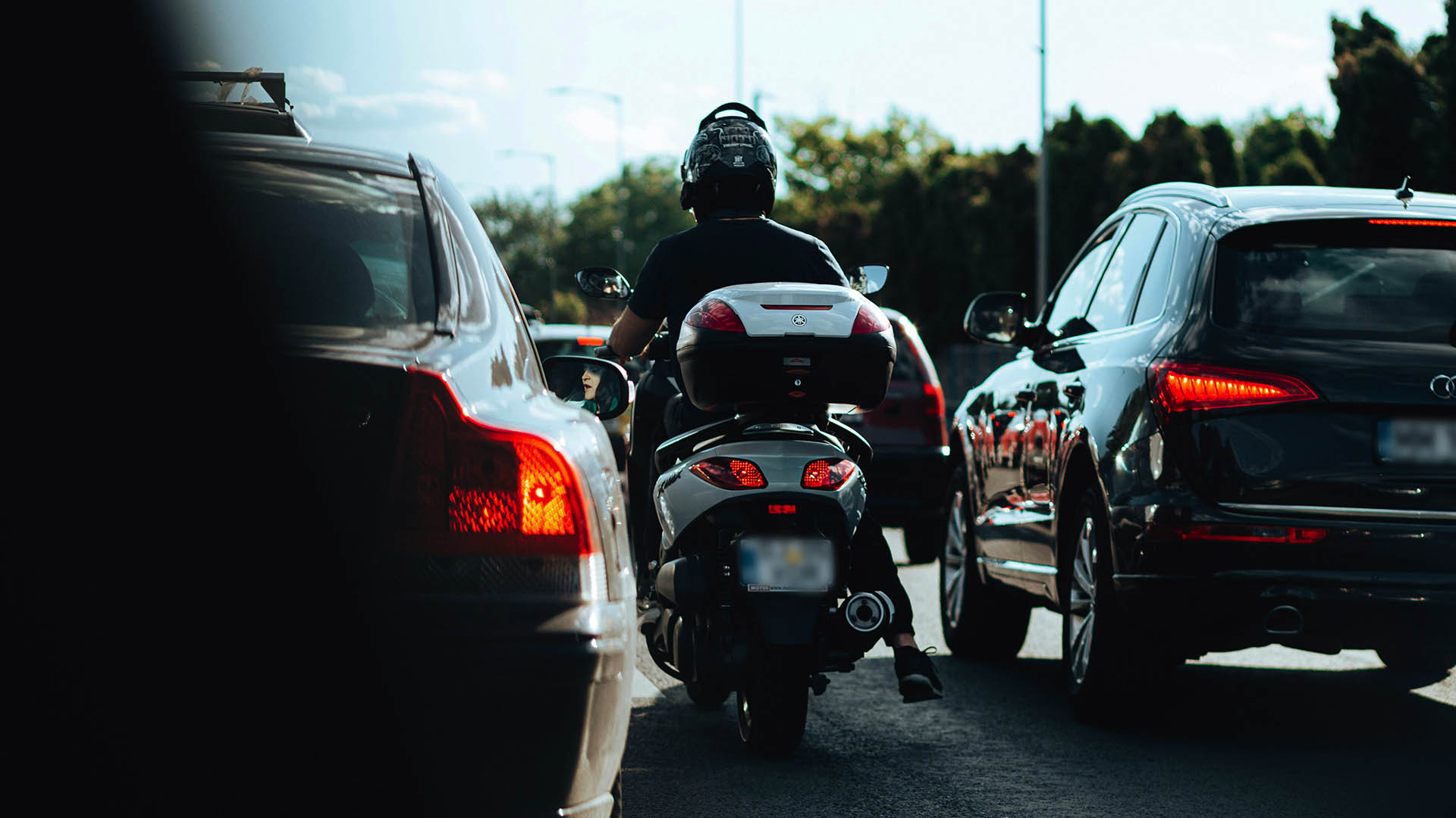 Motorka stojaca v kolóne vedľa áut